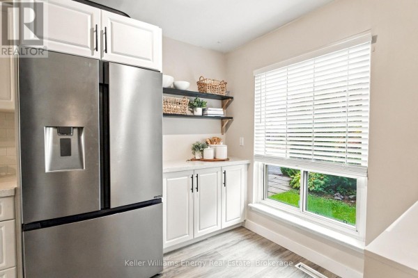 Kitchen features white cabinets, a stainless steel refrigerator, and a large window overlooking the front yard. - 61 - 155 Glovers Road, Oshawa