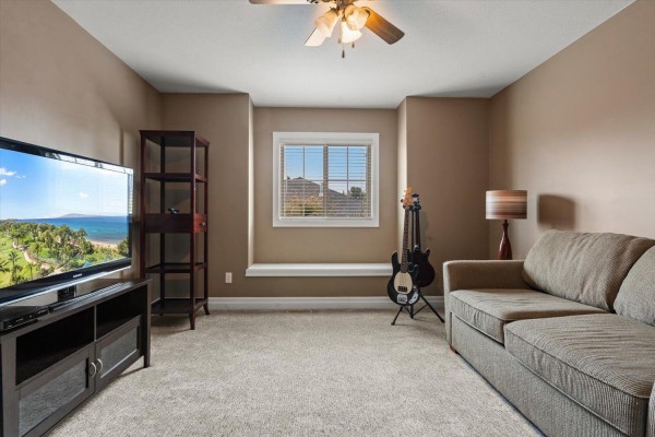 Cozy family room with a sofa, television, entertainment unit, and guitars. - 61 6449 Blackwood Lane, Sardis South, Chilliwack