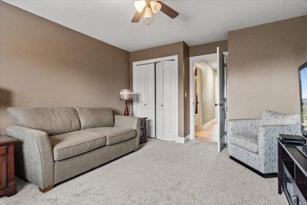 A spacious room with a sofa, armchair, closet doors, and a view of a hallway. - 61 6449 Blackwood Lane, Sardis South, Chilliwack