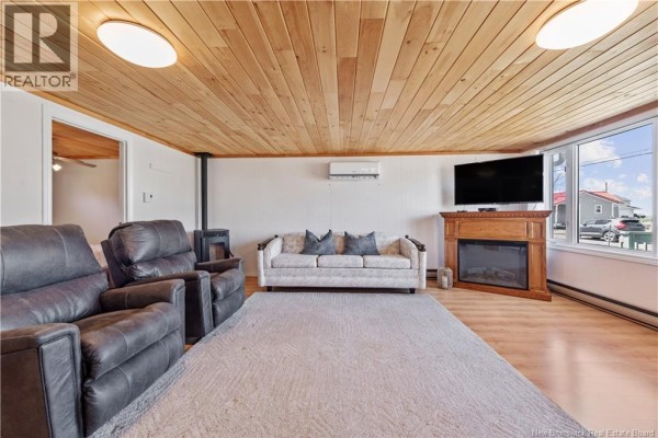 Living room with two recliners, sofa, fireplace, and TV, featuring a wood plank ceiling. - 61 Baybreeze Lane, Grand Barachois