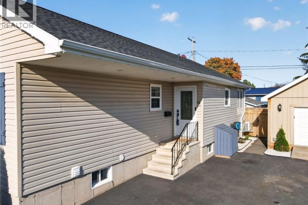 Close-up side view of the beige vinyl-sided bungalow entrance with beige siding and white trim. - 61 Bolton Street, Moncton