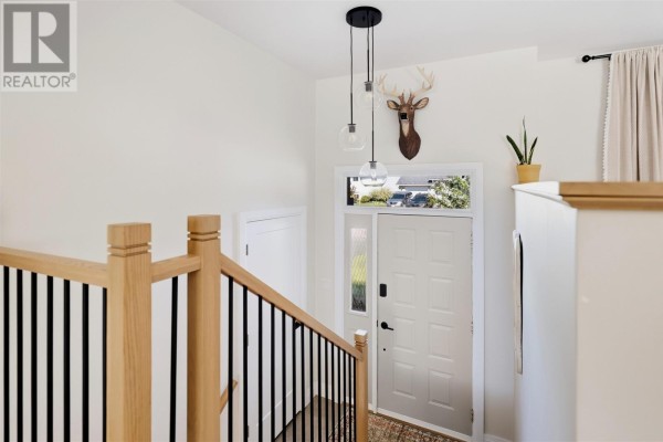 Interior view of a bright foyer with a white front door, staircase, and modern pendant lights. - 61 Bristol Pl, Sault Ste  Marie