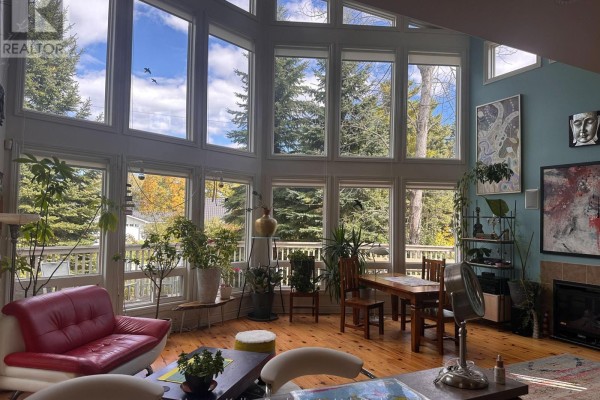 Living room with high ceilings, multiple large windows, wood floors, and a teal accent wall. - 61 Constance Blvd. Boulevard N, Wasaga Beach