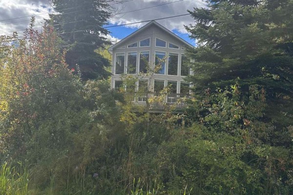 Exterior view of a house surrounded by trees with a large wall of windows. - 61 Constance Blvd. Boulevard N, Wasaga Beach