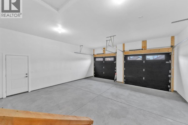 Two black garage doors with windows and a white interior door in a modern garage - 61 Hilton Court Amherstburg