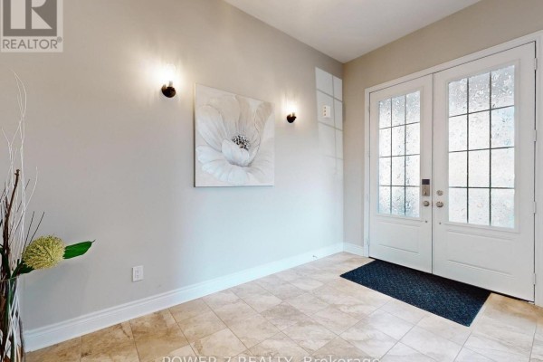 Interior entryway with tiled floor, double glass doors, and neutral wall art. - 61 Match Point Court, Aurora