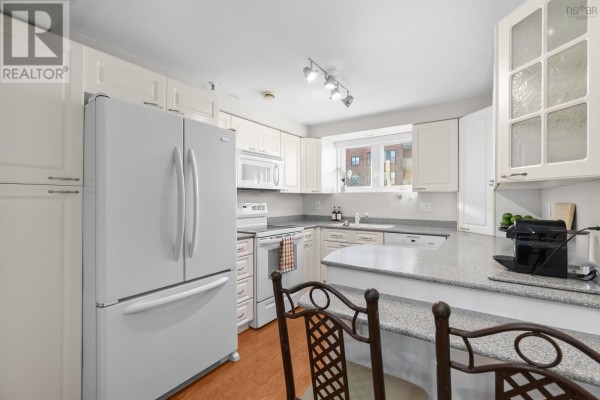 Apartment kitchen with white appliances, granite countertops, and breakfast bar. - 61 Nelsons Landing Boulevard, Bedford