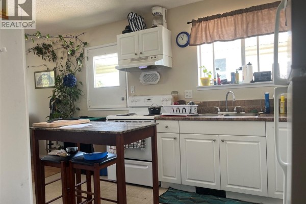 Kitchen with white cabinets, a white stove, and a butcher block island with two stools. - 61 View St, Nanaimo