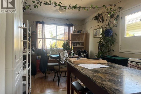 Dining area with a table and chairs near a window, surrounded by plants. - 61 View St, Nanaimo