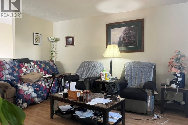 Living room with a colorful sofa, two recliner chairs, and a coffee table. - 61 View St, Nanaimo