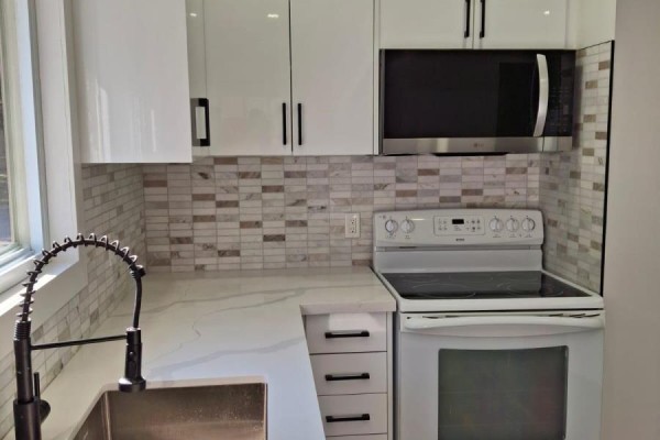 Modern kitchen with white high-gloss cabinets, a white countertop, and a stainless steel microwave. - 61 Wilkins Street, Quinte West
