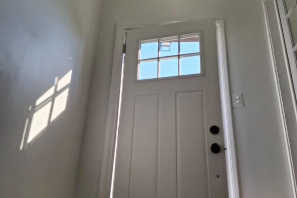Interior view of a white door with a glass pane, reflecting sunlight and shadows on the wall. - 61 Wilkins Street, Quinte West