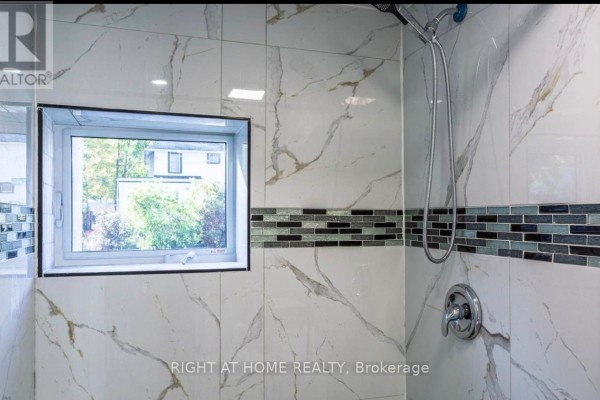 Bathroom with large white marble-look tiles, a glass shower enclosure, and a small window. - 61 Wilkins Street, Quinte West