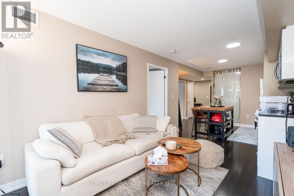 Living room with a sofa, coffee table, and view towards the kitchen island. - 610 - 151 Dan Leckie Way, Toronto
