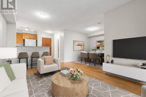 Open concept living space showing kitchen counter with stools, dining area, and living room seating. - 610 - 23 Lorraine Drive, Toronto