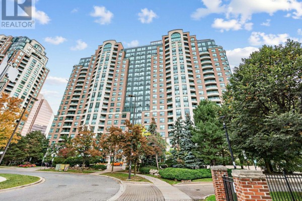 Exterior view of a tall, multi-story brick apartment building with balconies and surrounding trees. - 610 - 23 Lorraine Drive, Toronto