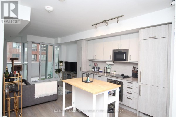 Open concept living area and kitchen with light wood cabinets, stainless steel appliances, and island. - 610 - 77 Mutual Street, Toronto