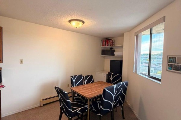 Dining area with a table, four chairs, and a window overlooking trees. - 610 1745 Leighton Rd, Victoria