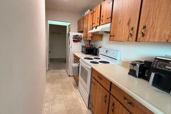 Narrow galley kitchen with light wood cabinets, white countertops, and white appliances. - 610 1745 Leighton Rd, Victoria
