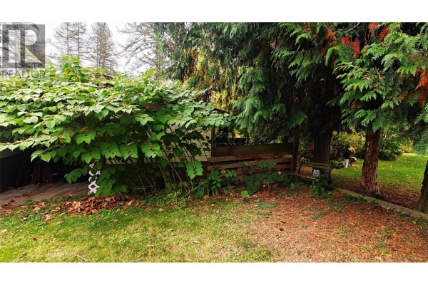 Shaded backyard area with dense green foliage, a wooden fence, and a shed. - 610 7th Avenue, Montrose