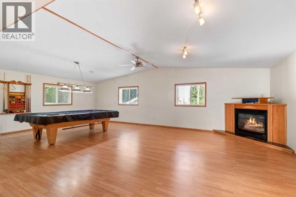 Large basement recreation room with a pool table, fireplace, and wood laminate flooring. - 610 8 Street N, Three Hills
