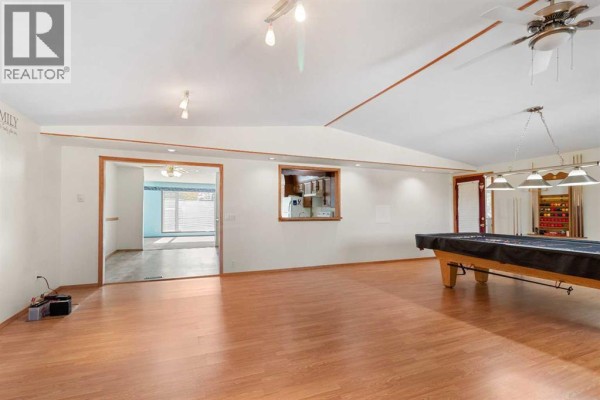 Spacious basement recreation room with a pool table and access to another room and exterior door. - 610 8 Street N, Three Hills