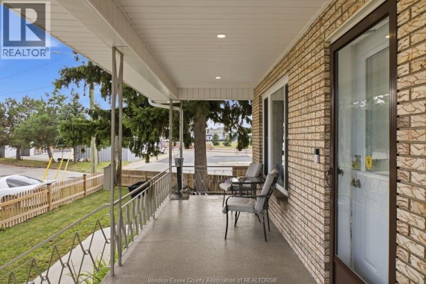 Covered front porch with metal railings, two chairs, a small table, and a brick facade. - 610 Brazil Avenue, Windsor