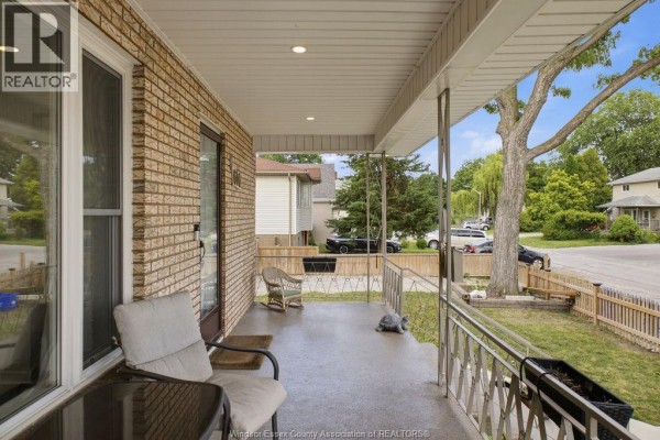 View from the porch showing seating, a rocking chair, and a view of the street and neighbouring houses. - 610 Brazil Avenue, Windsor