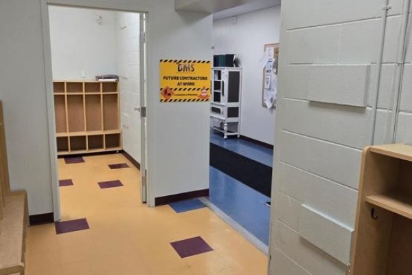 Interior hallway with light-colored cubbies, yellow and purple checkered flooring, and a door leading to another room. - 610 Dundas Street E, Belleville