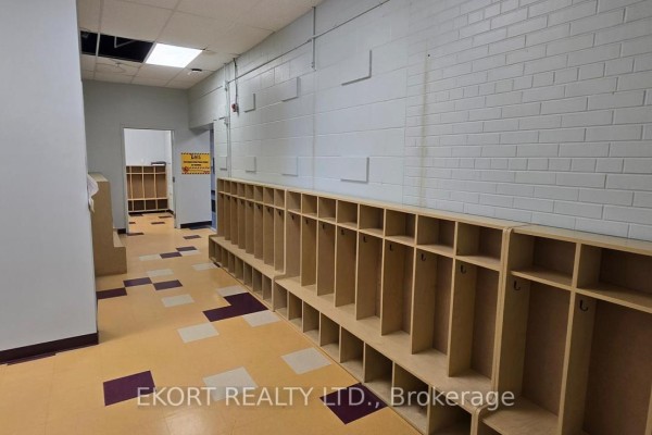 Interior hallway featuring long rows of light wood cubbies along the wall, light blue walls, and checkered flooring. - 610 Dundas Street E, Belleville