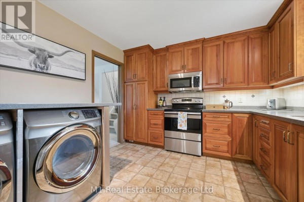 Wood cabinets, stainless steel appliances, tile floor, and washer/dryer - 610 St David Street S Centre Wellington