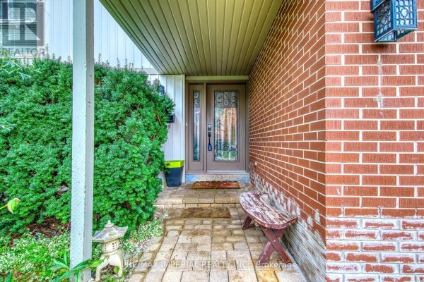 Front entrance with stone pavers, brick wall, and decorative glass double doors. - 6100 Wabukayne Court, Mississauga