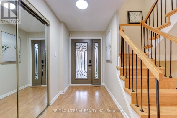 Interior hallway with wood floors, mirrored closet, double front doors, and staircase. - 6100 Wabukayne Court, Mississauga