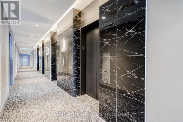 Hallway with black marble tiled walls, elevators, and patterned carpet. - 6102 - 5 Buttermill Avenue, Vaughan