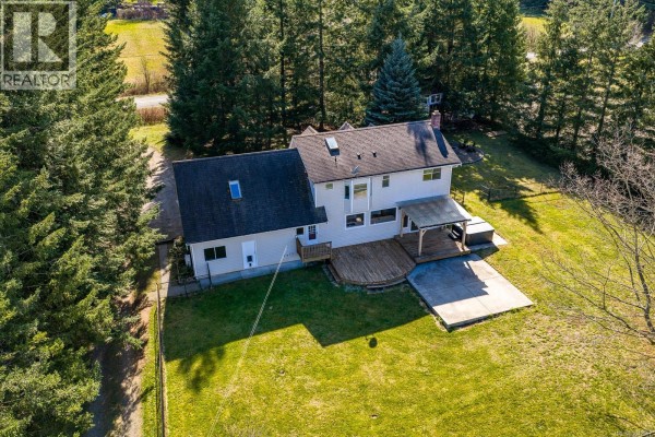 Aerial view of a residential property with a house, outbuildings, horse riding arena, and fenced pastures. - 6104 Ledingham Rd, Courtenay
