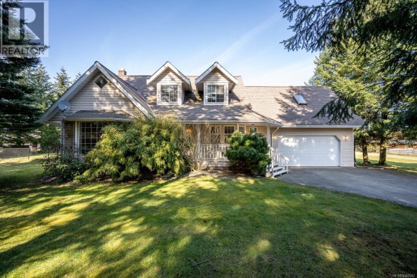 Living room featuring a white brick fireplace, large windows, glass sliding doors, and light wood-look floors. - 6104 Ledingham Rd, Courtenay