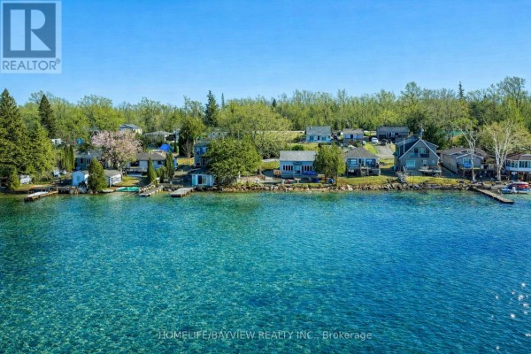 Waterfront properties lining a clear blue lake under a bright sky. - 6108 Curtis Pt Road, Alderville First Nation