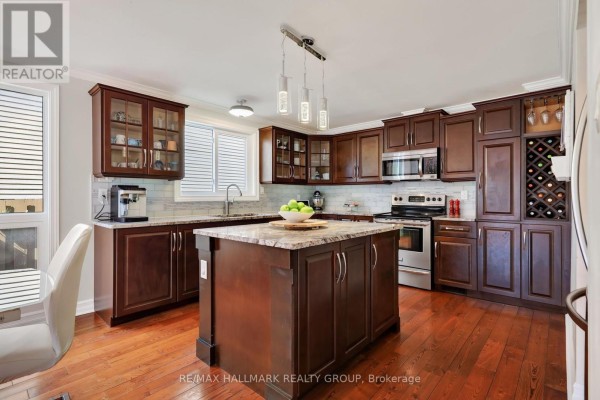 Kitchen with dark wood cabinets, granite countertops, stainless steel appliances, and island. - 6109 Forestglen Crescent, Ottawa