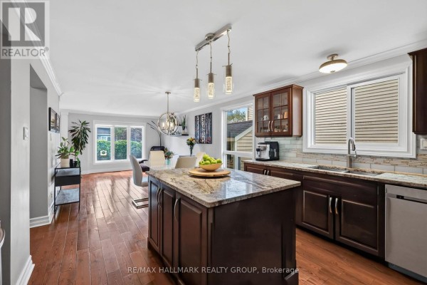 Open concept kitchen and dining area with island, dark wood cabinets, and hardwood floors. - 6109 Forestglen Crescent, Ottawa