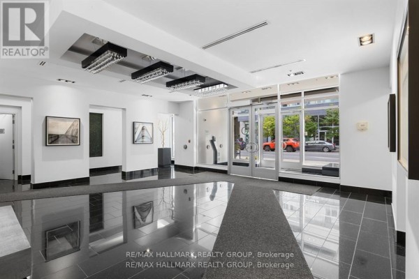 Lobby entrance with polished dark tile floors, modern artwork, and a view through glass doors. - 611 - 101 Richmond Road, Ottawa