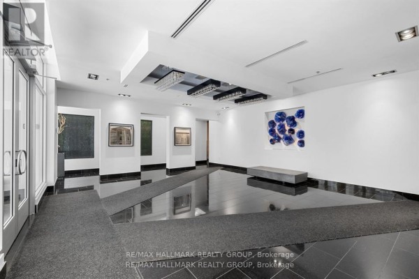 Wide view of the apartment lobby with a bench, abstract blue wall art, and tile floors. - 611 - 101 Richmond Road, Ottawa