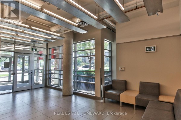 Building lobby with grey seating, concrete pillars, and large windows overlooking the street. - 611 - 170 Sudbury Street, Toronto