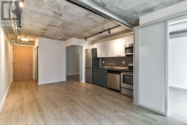 Open concept living area with light wood floors and a modern grey and white kitchen. - 611 - 170 Sudbury Street, Toronto