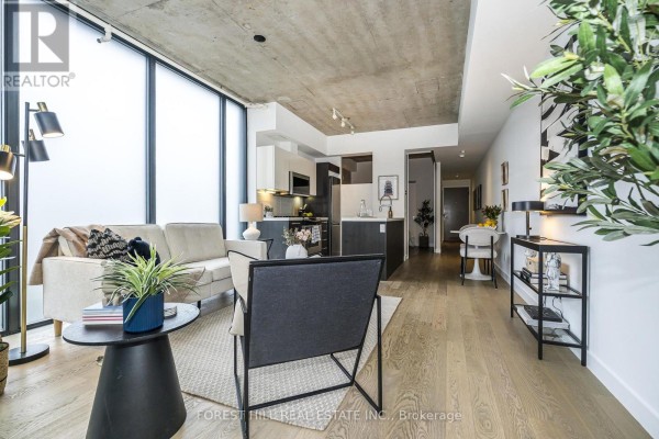 Living space with concrete ceiling, frosted windows, column, and sliding glass doors leading to a balcony. - 611 - 25 Stafford Street, Toronto