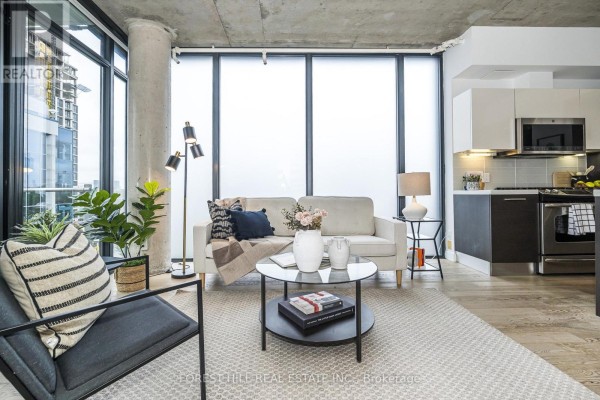 Kitchen island with sink, dining table with chairs, and living area with sofa and balcony view. - 611 - 25 Stafford Street, Toronto
