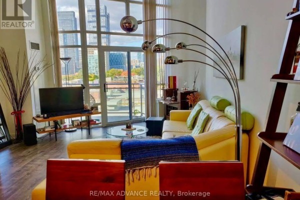 Living room with a sectional sofa, large windows, city view, and modern floor lamp. - 611 - 255 Richmond Street E, Toronto