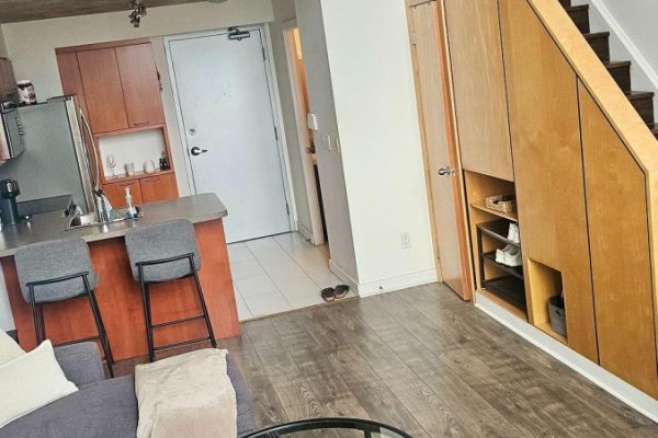 Living area with kitchen island, stairs, and built-in wooden storage units. - 611 - 255 Richmond Street E, Toronto