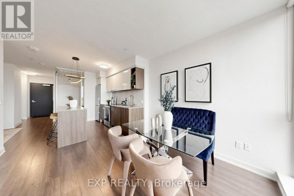 Dining area with glass table and chairs, overlooking kitchen and living space. - 611 - 31 Tippett Road, Toronto