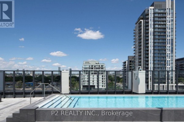 A rooftop swimming pool with steps and a glass railing, surrounded by buildings under a blue sky. - 611 - 36 Zorra Street, Toronto
