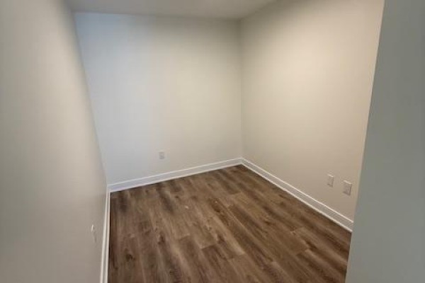 Empty room with light grey walls, light wood flooring, and white baseboards. - 611 - 86 Dundas Street E, Mississauga